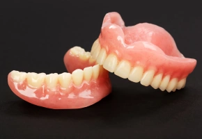 Upper and lower full dentures sitting together on a dark background