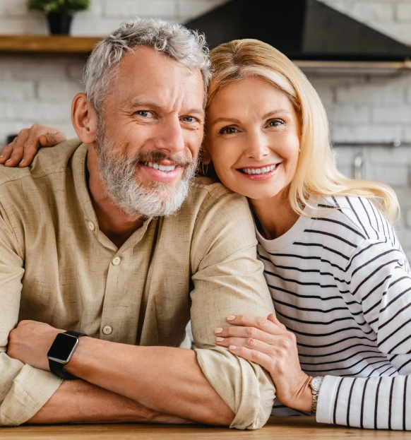 Happy older couple smiling after replacing missing teeth with dentures